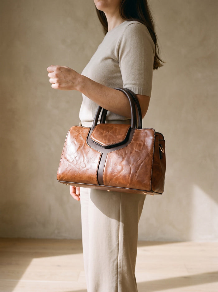 The Marlow Bag in Brown, held by the top handle at the hip