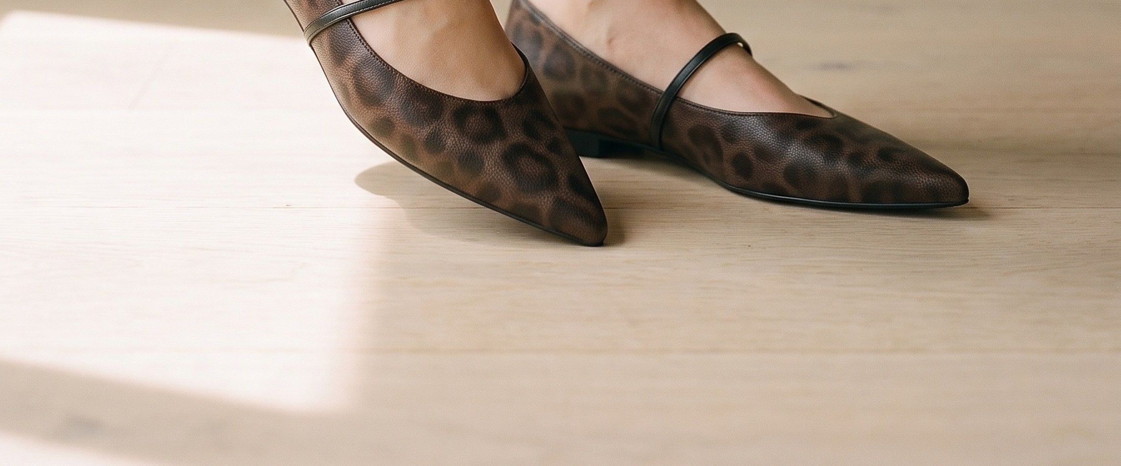 Pointed flats in a brown animal print, worn