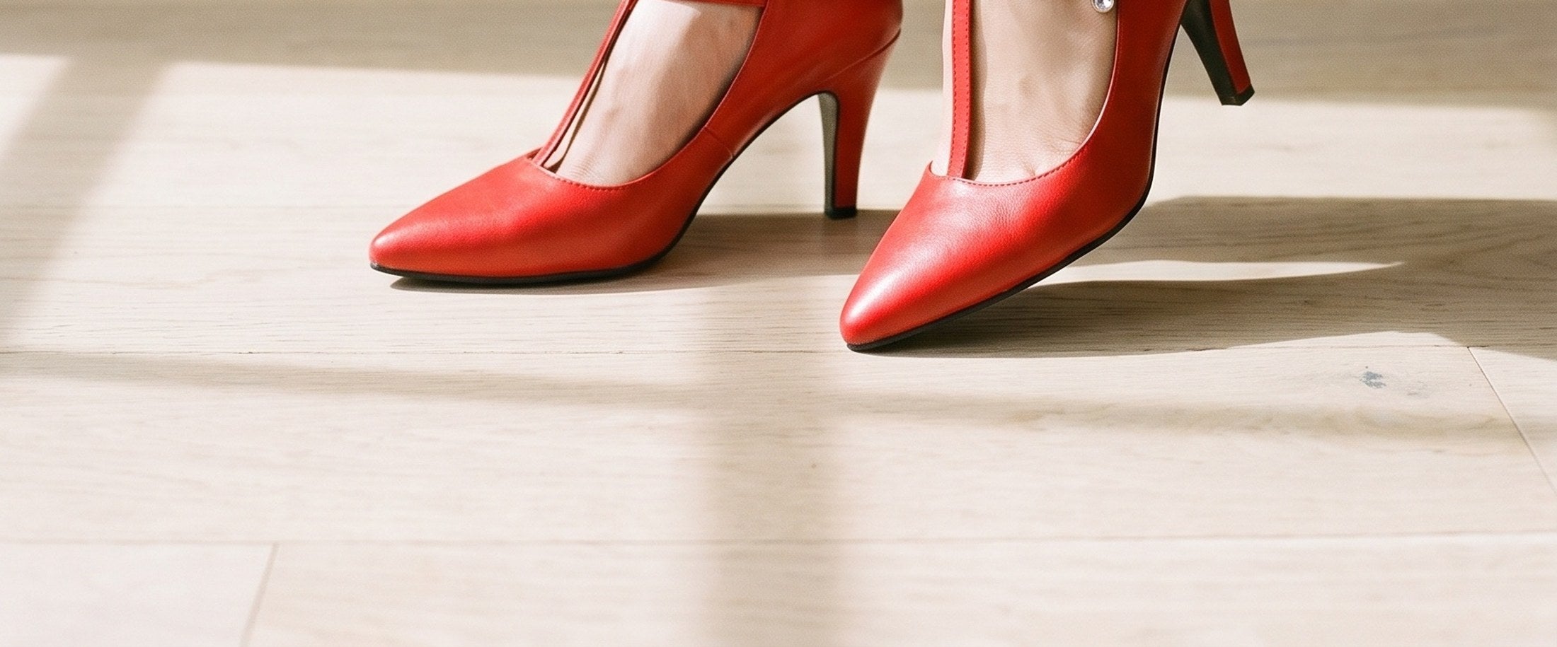 Red T-bar heels, worn on a pale oak floor