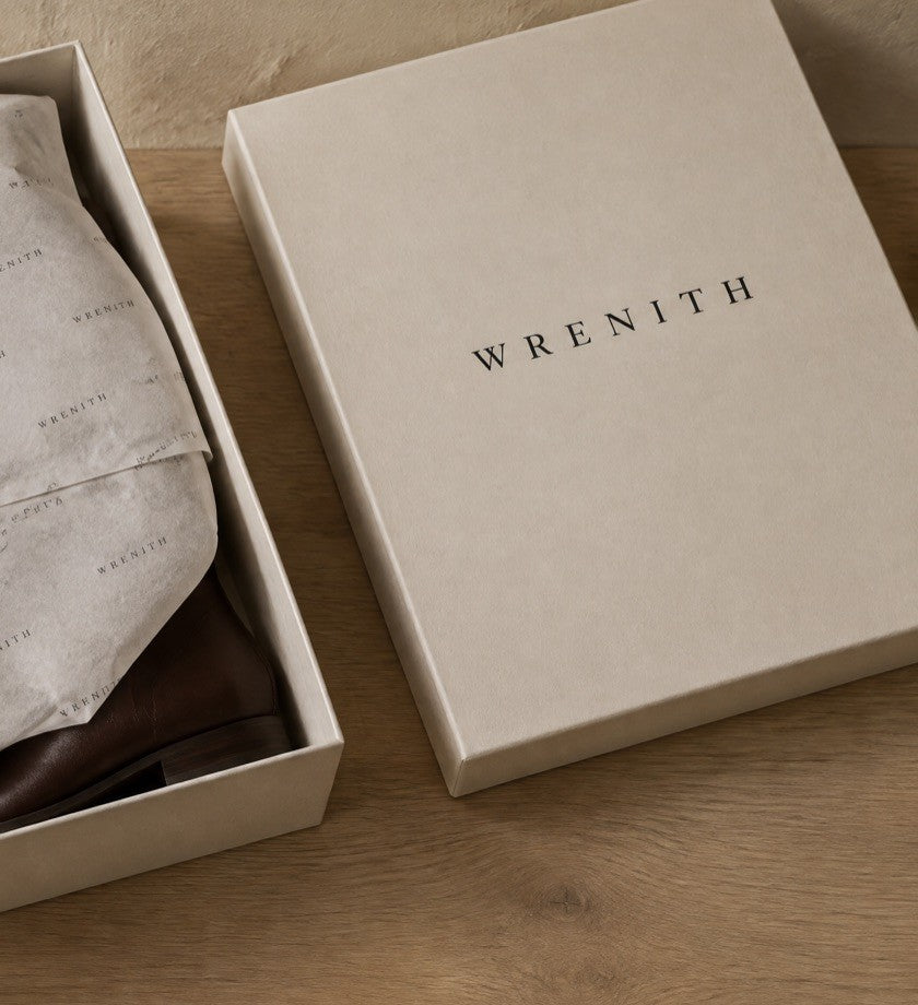 A Wrenith box open, the boots wrapped in tissue printed with the wordmark